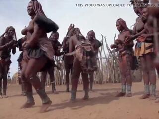 Afrikāņu himba sievietes deja un šūpoles viņu saggy bumbulīši apkārt